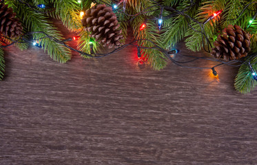 Christmas decorations with branches of fir tree, christmas lights, ball and Pine cones on wooden background. copy space