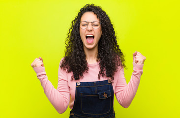 young pretty woman feeling happy, positive and successful, celebrating victory, achievements or...