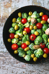Brussels sprouts in a pan with cherry tomatoes, garlic and olives before baking. Healthy food. Vegan diet. Vegetable pan.