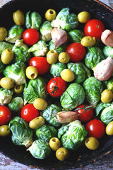 Brussels sprouts in a pan with cherry tomatoes, garlic and olives before baking. Healthy food. Vegan diet. Vegetable pan.