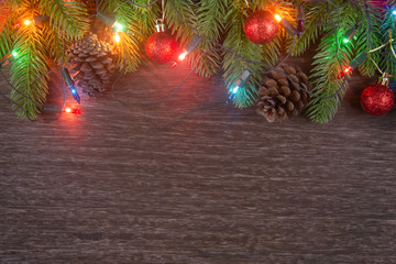 Christmas decorations with branches of fir tree, christmas lights, ball and Pine cones on wooden background. copy space