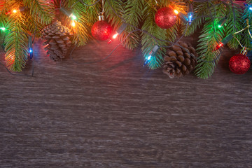 Christmas decorations with branches of fir tree, christmas lights, ball and Pine cones on wooden background. copy space