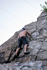 Bottom view of a young climber hanging on a rock, free space.