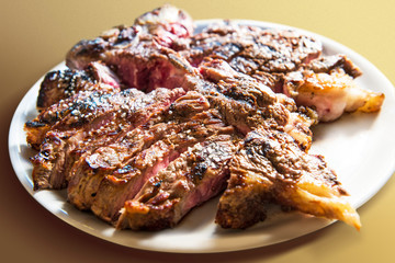 White round plate with cut grilled T-bone steak