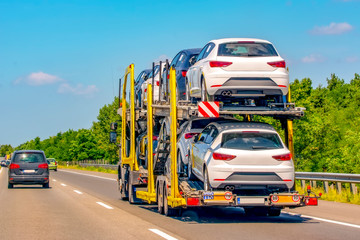 Truck trailer transports new cars rides on highway,