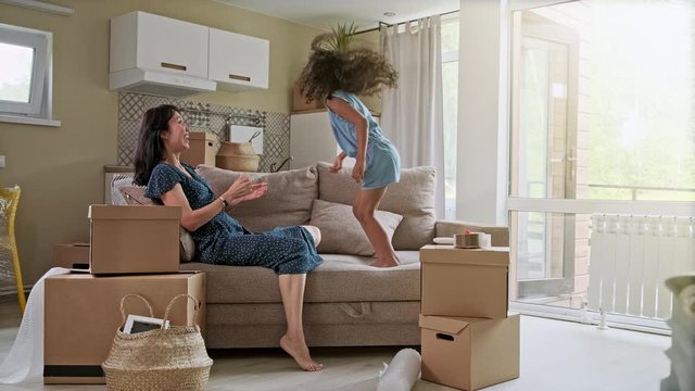 Young mother and her little daughter jumping on bed. Funny pillow fight. Play together and enjoy the moment! Family time on weekend.