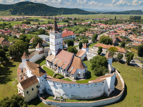 Aerial view of fortified church surrounded powerful thick walls in Transylvania overlooking the village in a beautiful summer day. Romania.