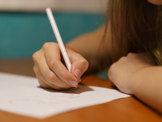 Schoolgirl doing homework in math. She doing sums. She sitting at the table. High resolution...