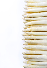 Raw white Asparagus beaded in a row as closeup with copy space left – isolated on white background