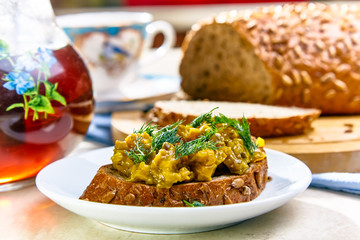 Sandwich with relish with cucumbers lies on a white plate on the background of bread