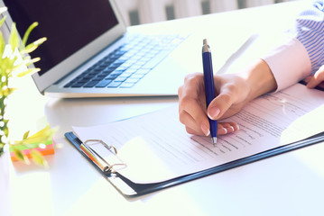 Businesswoman sitting at office desk signing a contract or making notes.