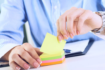 Accountant woman tears off color sticker, close up.