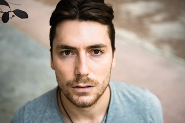 Fototapeta premium Handsome male model in gray shirt looking at camera with calm pose.