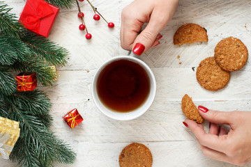 Christmas composition with hands keeping tea mug and cookies