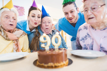 Senior men and women celebrating birthday in retirement home