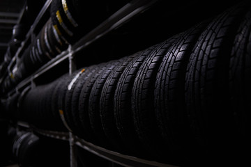 Naklejka na ściany i meble Dark storage full or big variety of new tyres at busy warehouse.