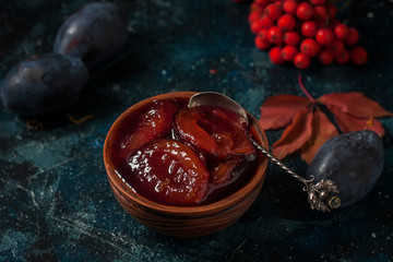 Homemade plum jam and fruits on a wooden table.
