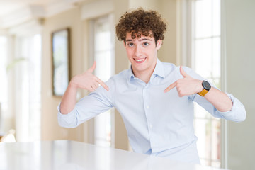 Young business man with curly read head looking confident with smile on face, pointing oneself with...