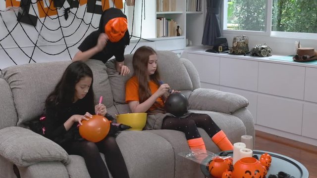 Halloween party kids smiling happy to play and prepare decoration toy balloon for Halloween day coming soon in living room at home together, slow motion