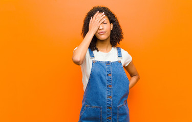 young pretty black woman laughing and slapping forehead like saying d‚Äôoh! I forgot or that...