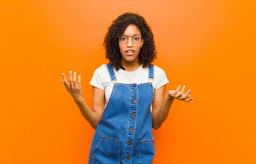 young pretty black woman feeling clueless and confused, not sure which choice or option to pick,...