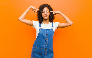 young pretty black woman with a serious and concentrated look, brainstorming and thinking about a...