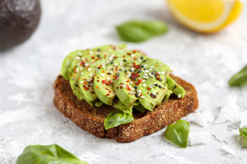 Avocado sandwich. Vegan snack for lunch. Healthy food. Fresh green slice on rye bread. Gourmet organic dish for breakfast. Simple health fitness recipe with lemon, chili,basil, sesame