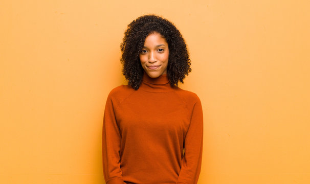 Young Pretty Black Woman Smiling Positively And Confidently, Looking Satisfied, Friendly And Happy Against Orange Wall