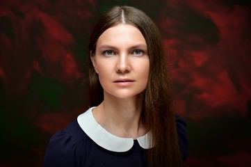 Close-up portrait of a pretty young brunette woman with combed hair over color background. Looks straight at the camera. Great facial skin.