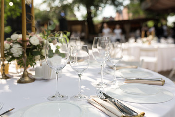 Wedding table setting decorated with fresh flowers in a brass vase. Wedding floristry. Banquet...