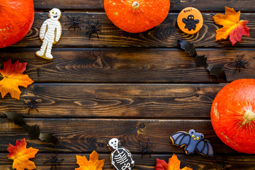 Halloween frame with pumpkins, paper bats and special cookies on dark wooden background top view...