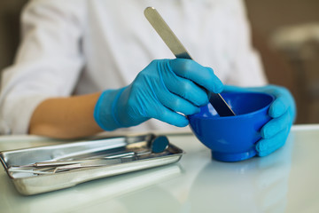 Closeup hands female dentist doctor knead the mass in the flask..