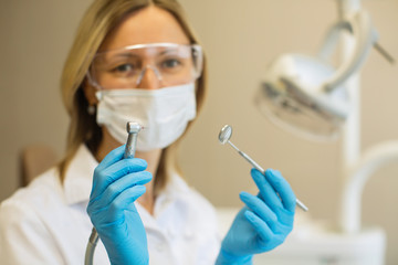 Female dentist doctor holding and showing closeup a tooling.