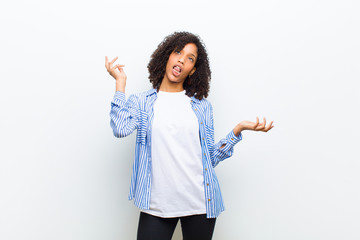young cool african american woman shrugging with a dumb, crazy, confused, puzzled expression,...