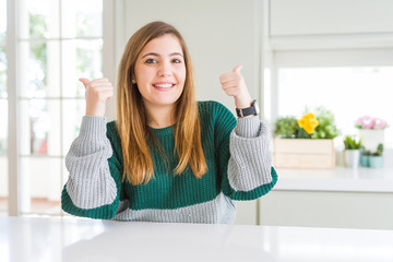 Young beautiful plus size woman wearing casual striped sweater success sign doing positive gesture with hand, thumbs up smiling and happy. Cheerful expression and winner gesture.