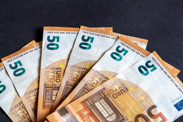 View of several fifty Euro banknotes in different arrangements against black background