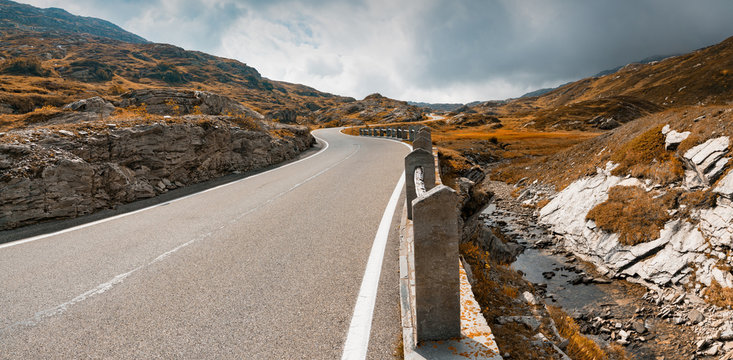 two-lane road leading over a high remote and wild mountain pass in the Swiss Alps in autumn