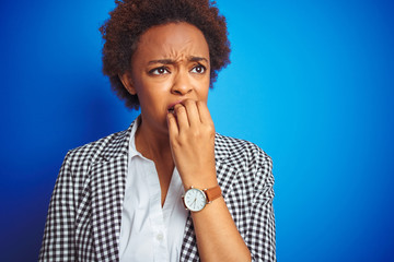 Fototapeta na wymiar African american business executive woman over isolated blue background looking stressed and nervous with hands on mouth biting nails. Anxiety problem.