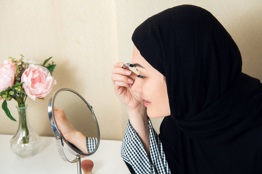 Beautiful muslim woman applying mascara. Young arab woman using lash brush