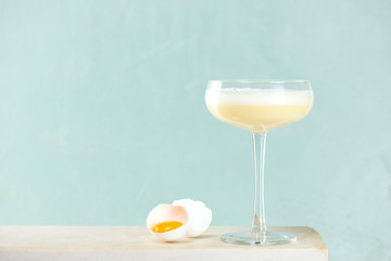 Glass of Eggnog and egg on the white marble table against the light blue wall