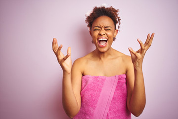 African american woman wearing shower towel after bath over pink isolated background celebrating mad and crazy for success with arms raised and closed eyes screaming excited. Winner concept