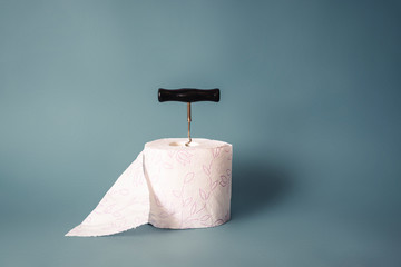 Constipation concept. Roll of toilet paper and a corkscrew on blue background