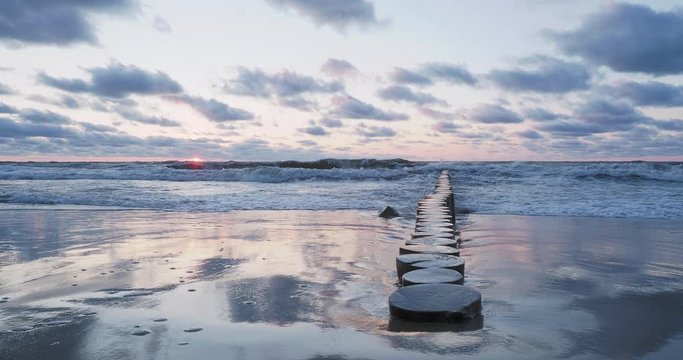 Breakwater of larch logs. Strengthening the seashore to keep the sand on the beach. Gorgeous sunset in Zelenogradsk, Russia.