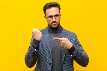 young handsome man looking impatient and angry, pointing at watch, asking for punctuality, wants to...
