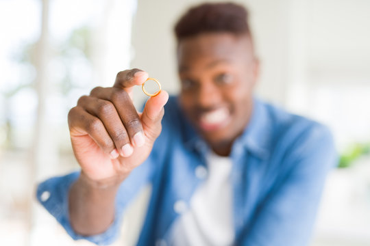Close up of african man hand holding golden alliance as romatic marriage symbol smiling cheerful