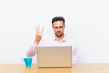 young handsome businessman smiling and looking friendly, showing number three or third with hand...