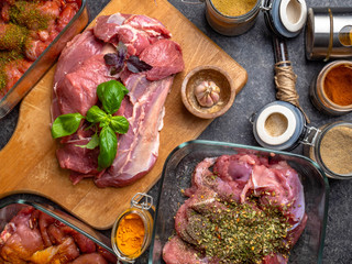 Raw meat background. with a variety of herbs and spices. On the grey concrete table.