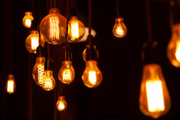 classic different retro light bulbs hanging on brick wall background at night