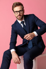 businessman sitting with one hand resting and the other  raised