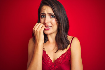 Fototapeta premium Young beautiful woman wearing sexy lingerie over red isolated background looking stressed and nervous with hands on mouth biting nails. Anxiety problem.